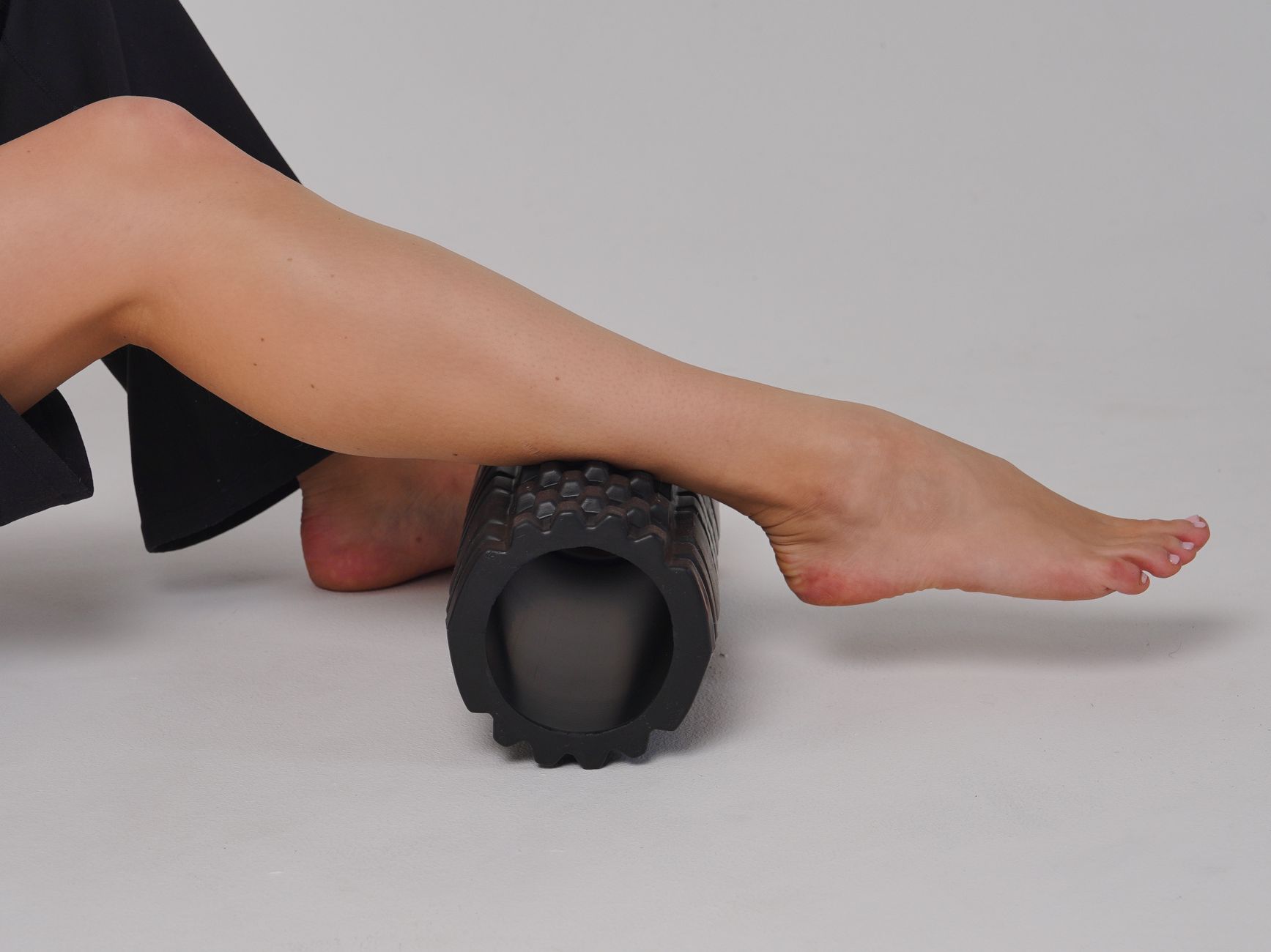 Jambe posée sur un rouleau de massage à texture grid, utilisation au sol