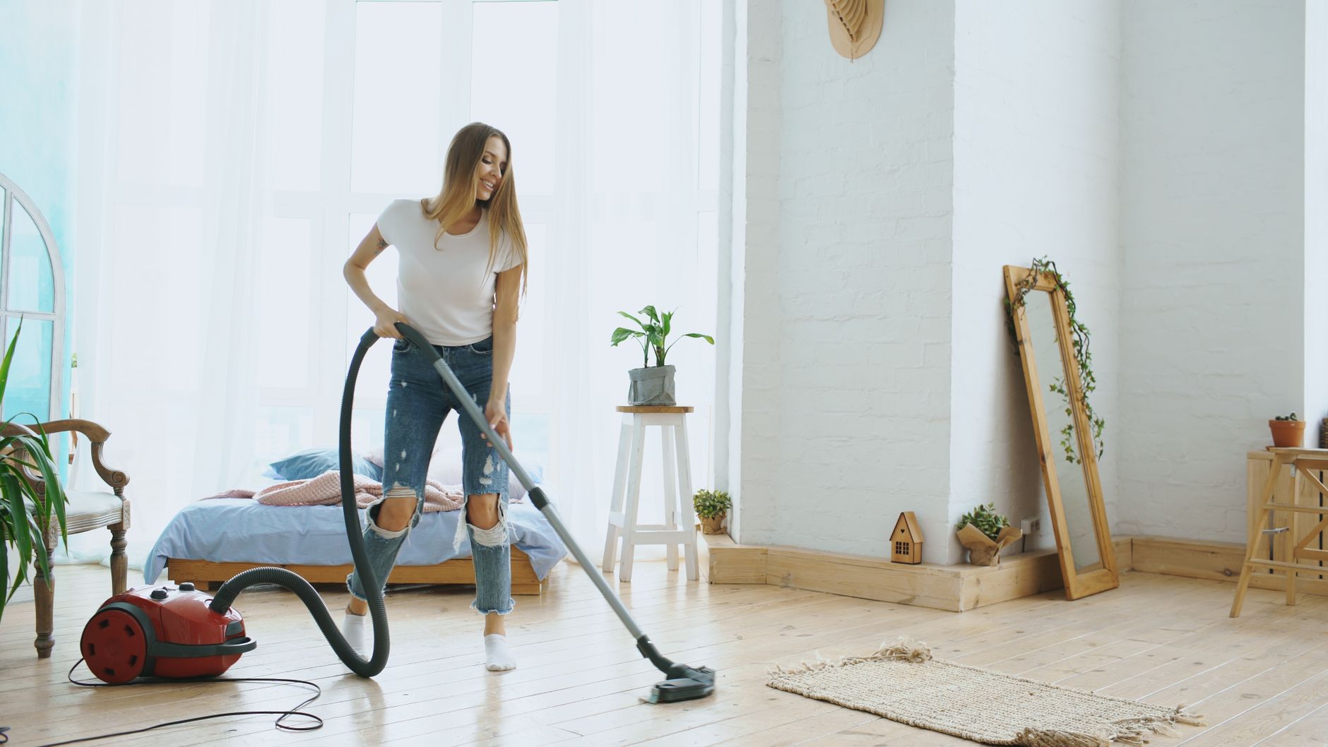 Personne passant l'aspirateur près du lit dans une chambre lumineuse