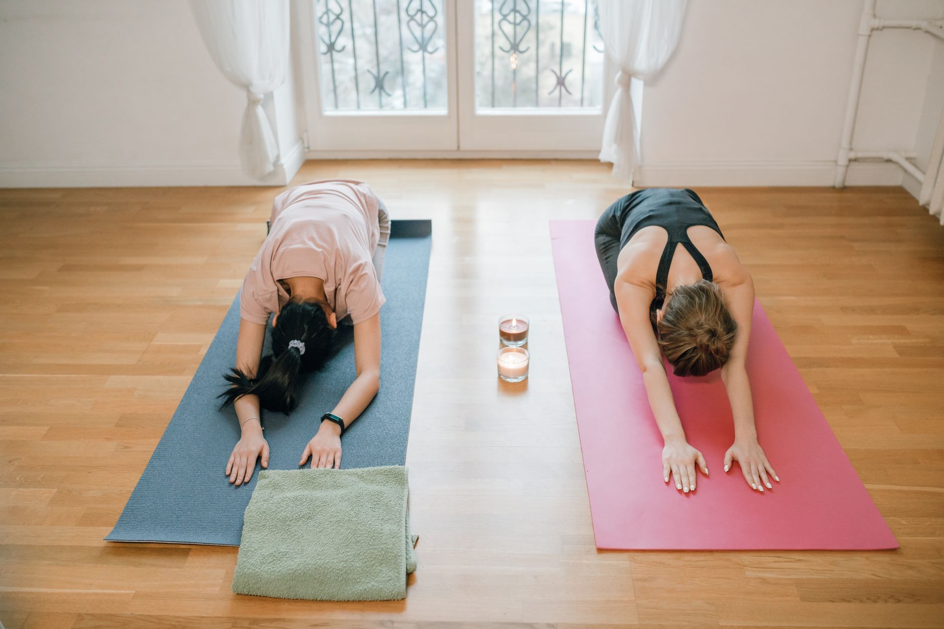Deux femmes pratiquant le yoga sur tapis en intérieur.