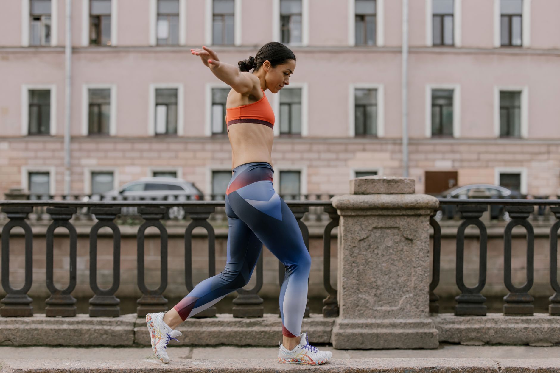 Femme en tenue de sport colorée en équilibre sur un trottoir.