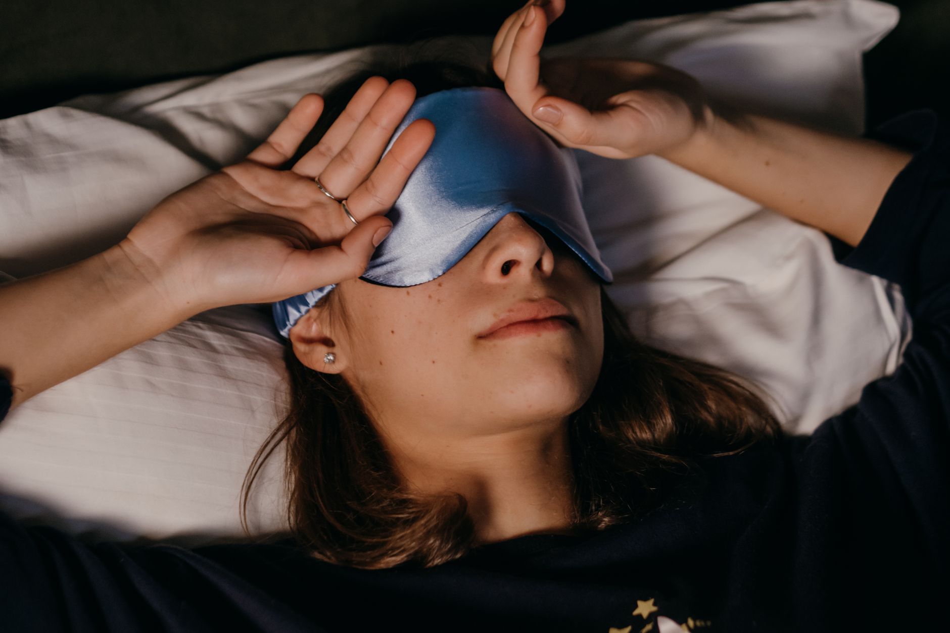 Femme reposant paisiblement avec masque de sommeil en intérieur confortable.