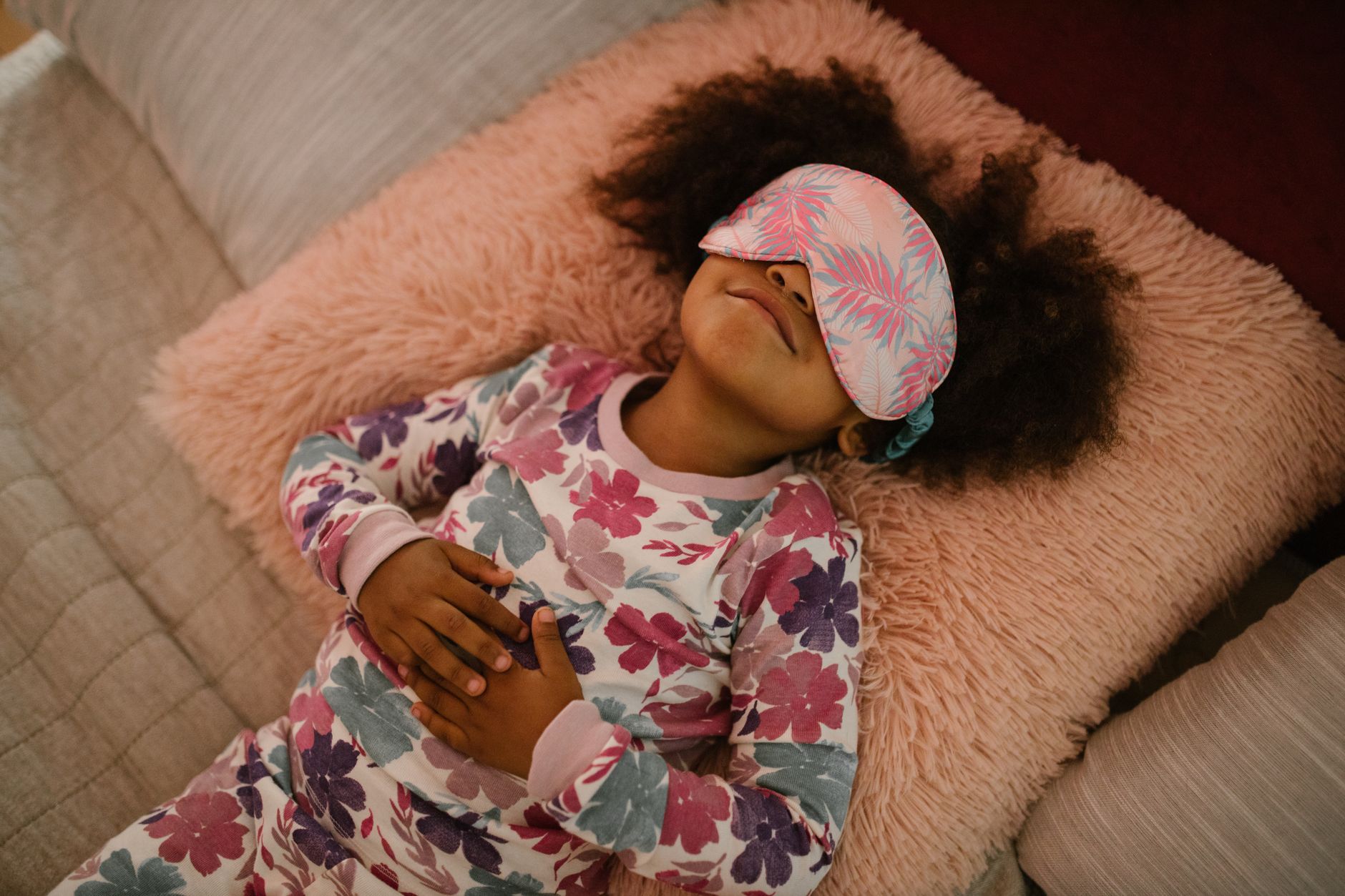 Jeune fille en pyjama fleuri et masque de sommeil reposant paisiblement.