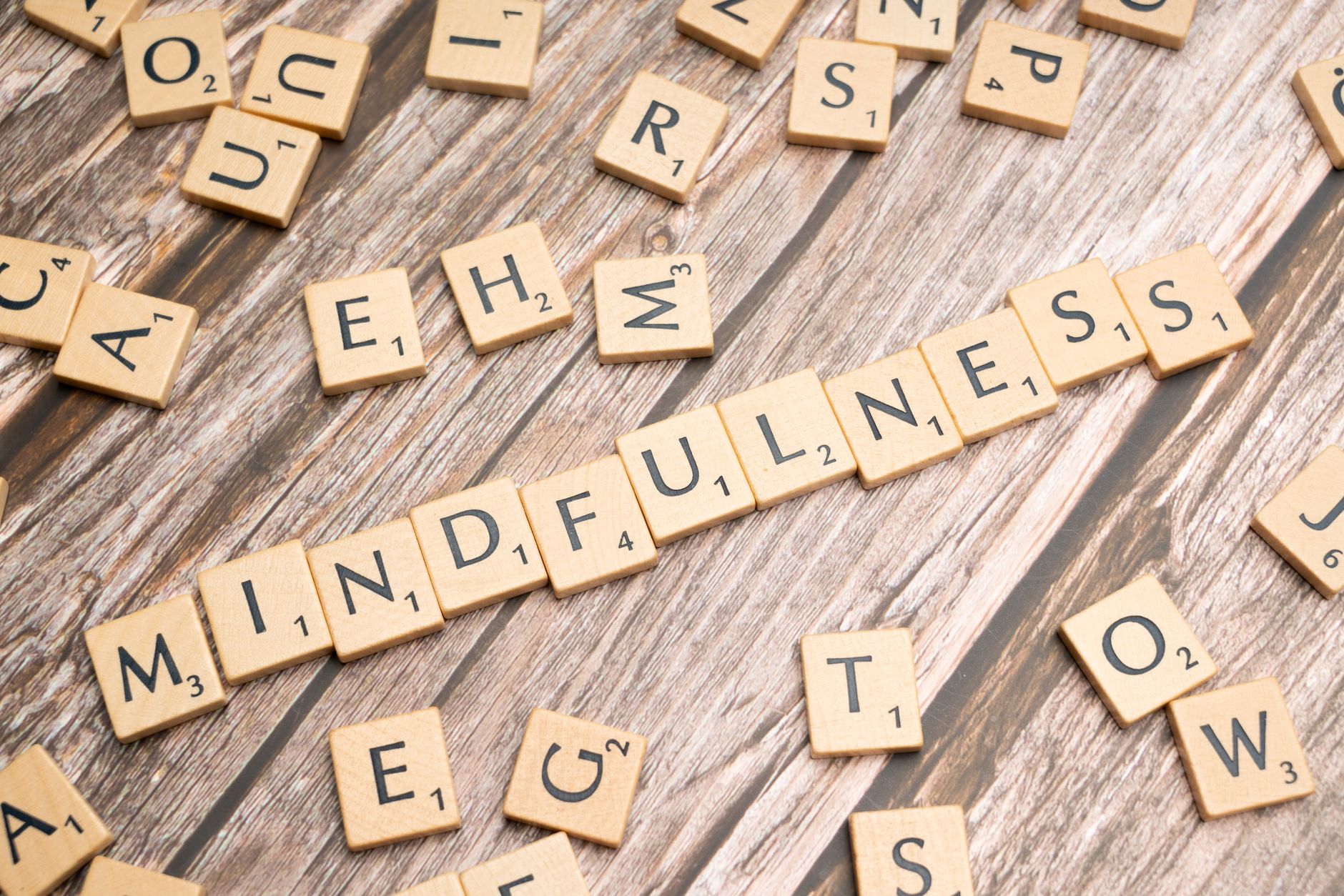 Lettres en bois formant le mot « mindfulness » sur fond en bois rustique.