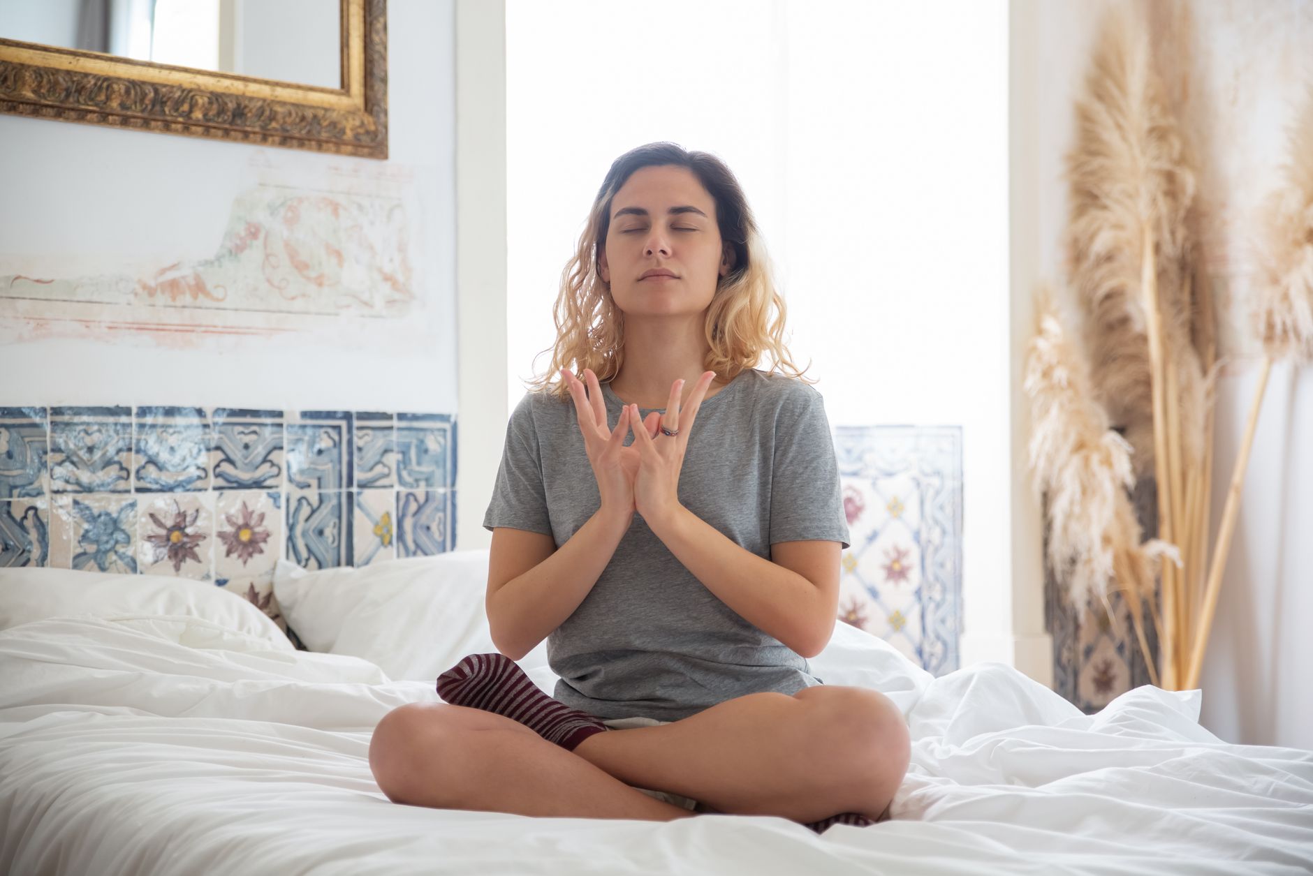 Femme méditant dans une chambre paisible avec lumière naturelle douce.