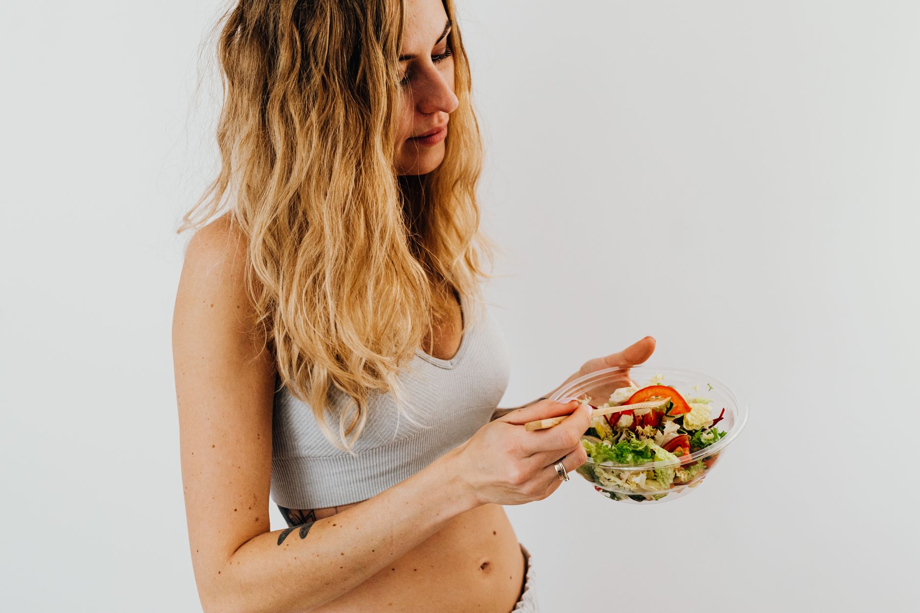 Femme caucasienne en brassière mangeant une salade fraîche.