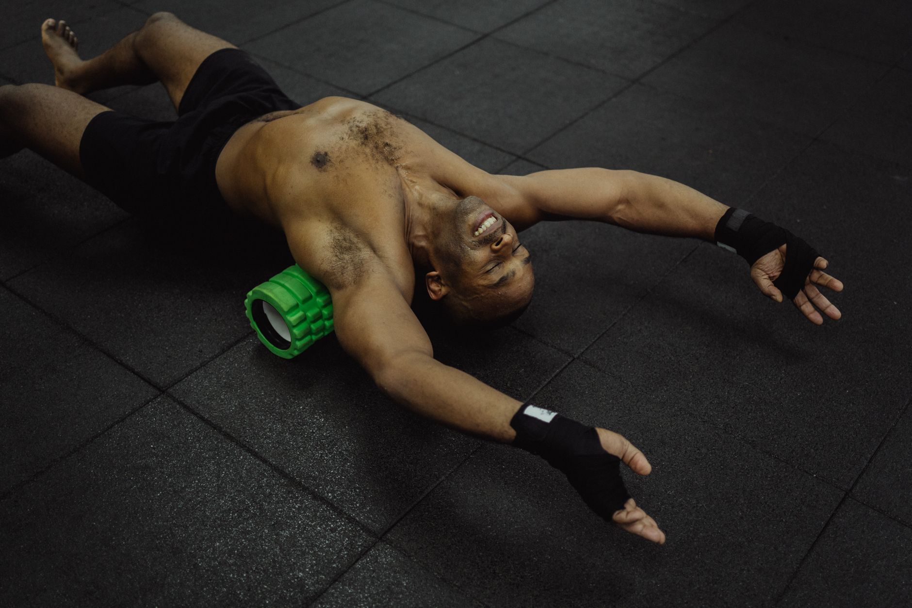 Homme torse nu s’exerçant avec rouleau en mousse en salle de sport.