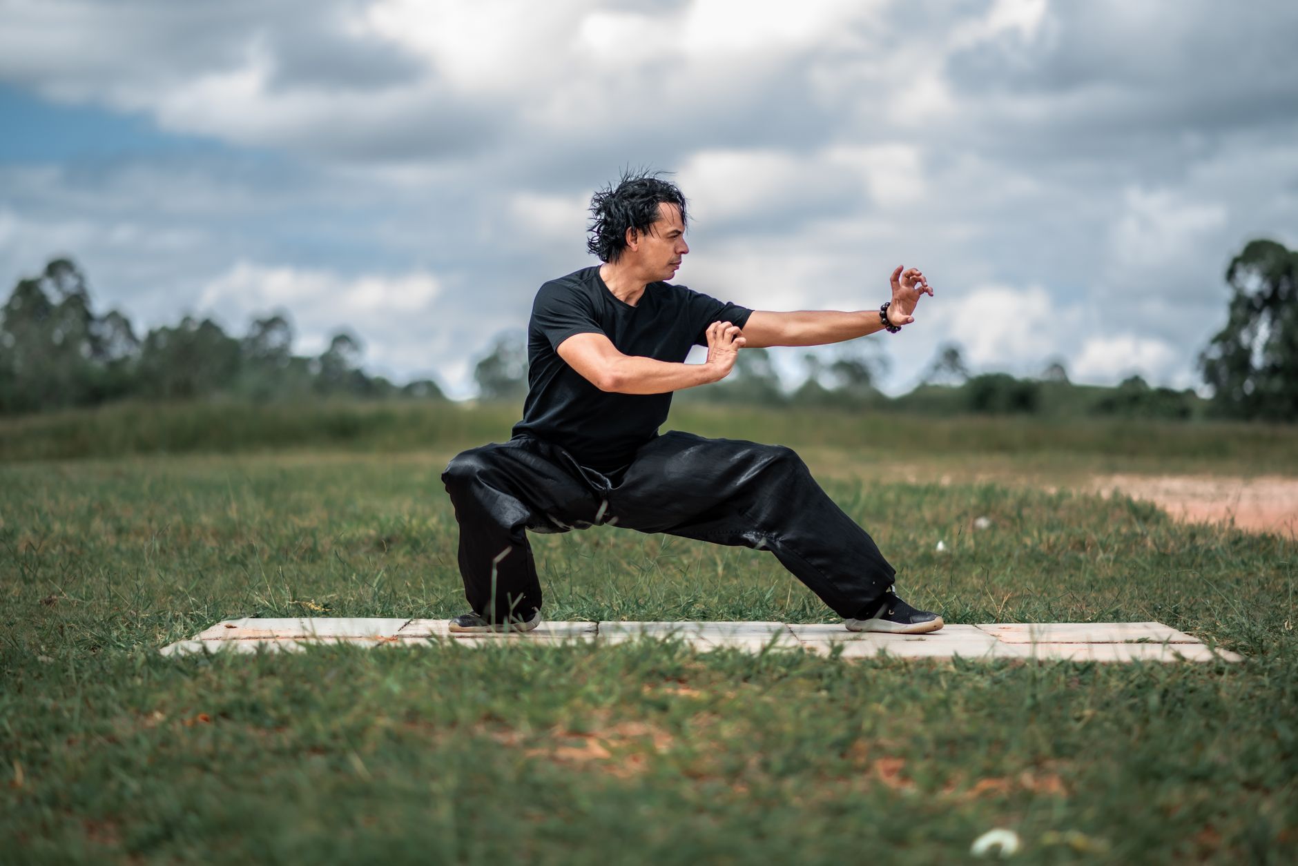 Homme pratiquant tai chi en extérieur paisible.