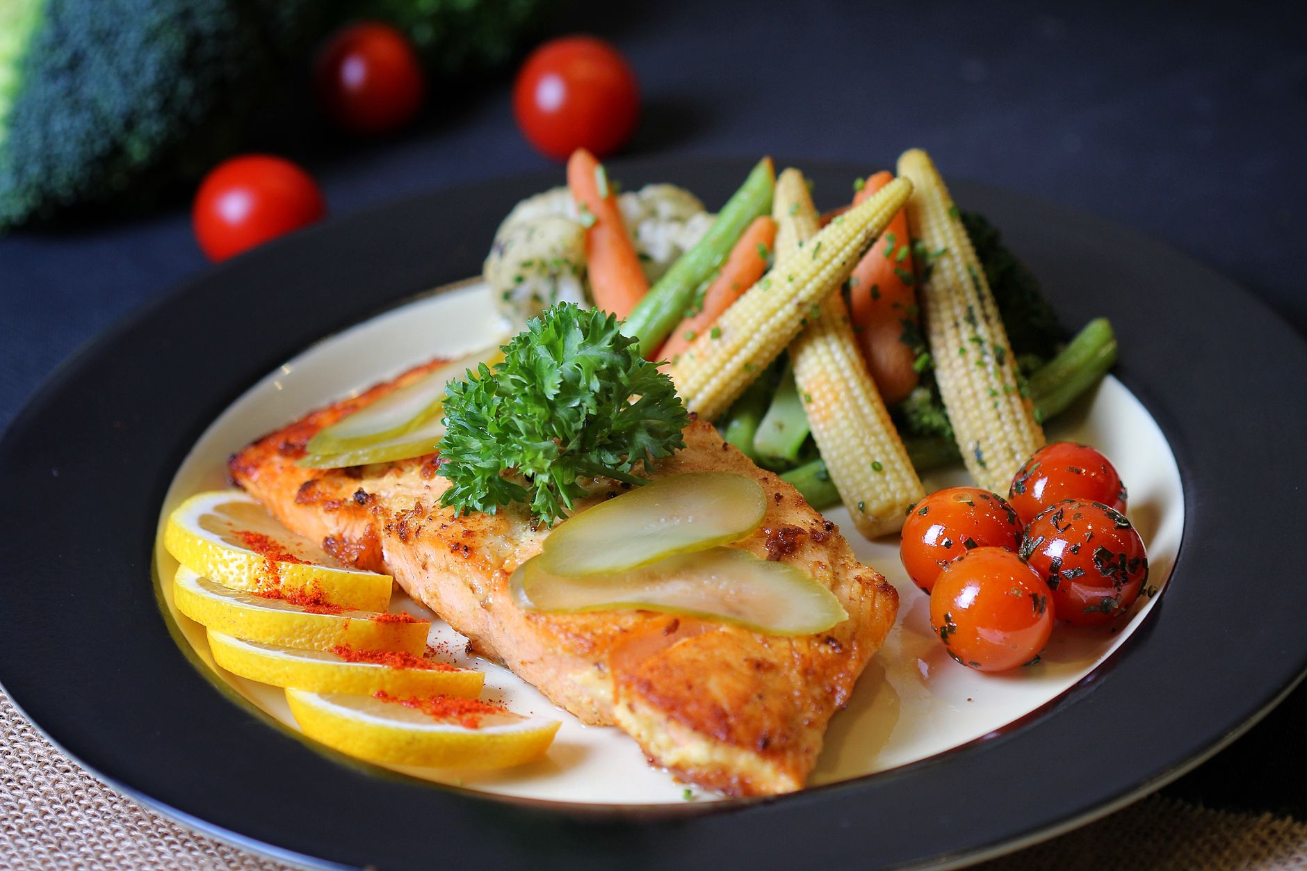 Assiette colorée de poisson grillé avec citron, cornichons et légumes frais.