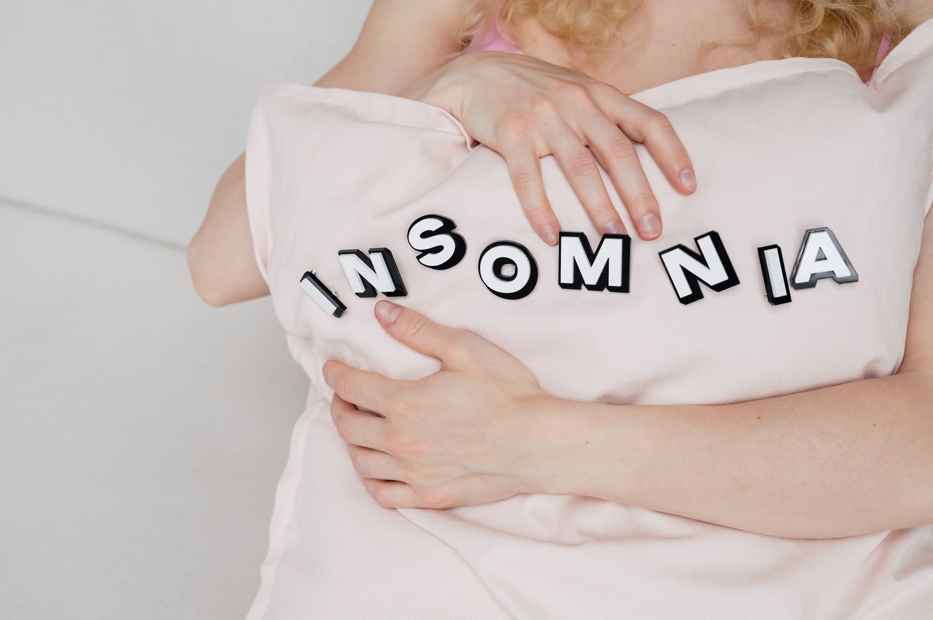 Gros plan d’une femme tenant un oreiller avec texte sur insomnie.