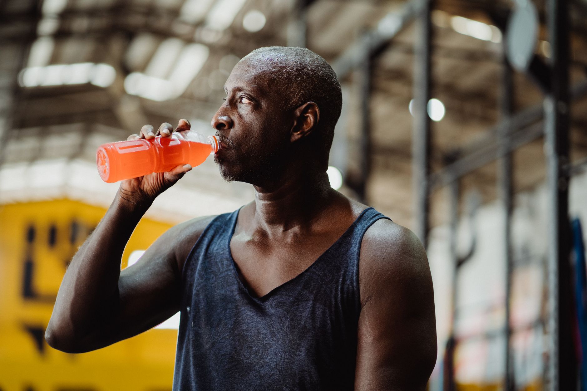 Homme en forme buvant une boisson froide pendant sa pause à la salle de sport.