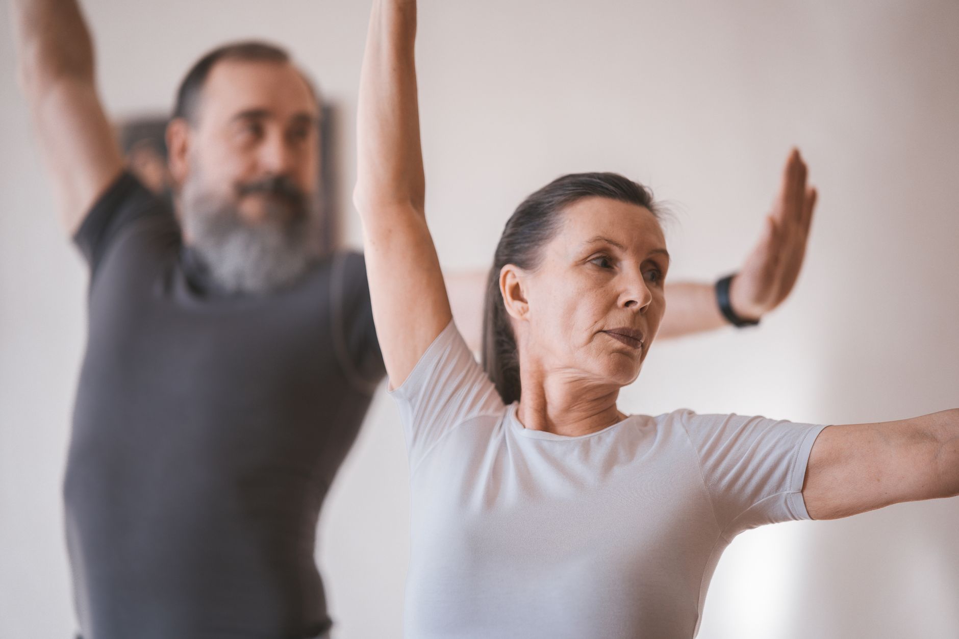 Personnes âgées en séance de yoga intérieur, axée sur étirements et équilibre.