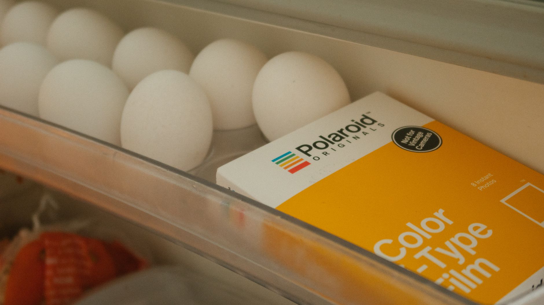 Gros plan d’œufs frais et boîte de pellicule Polaroid dans un frigo.
