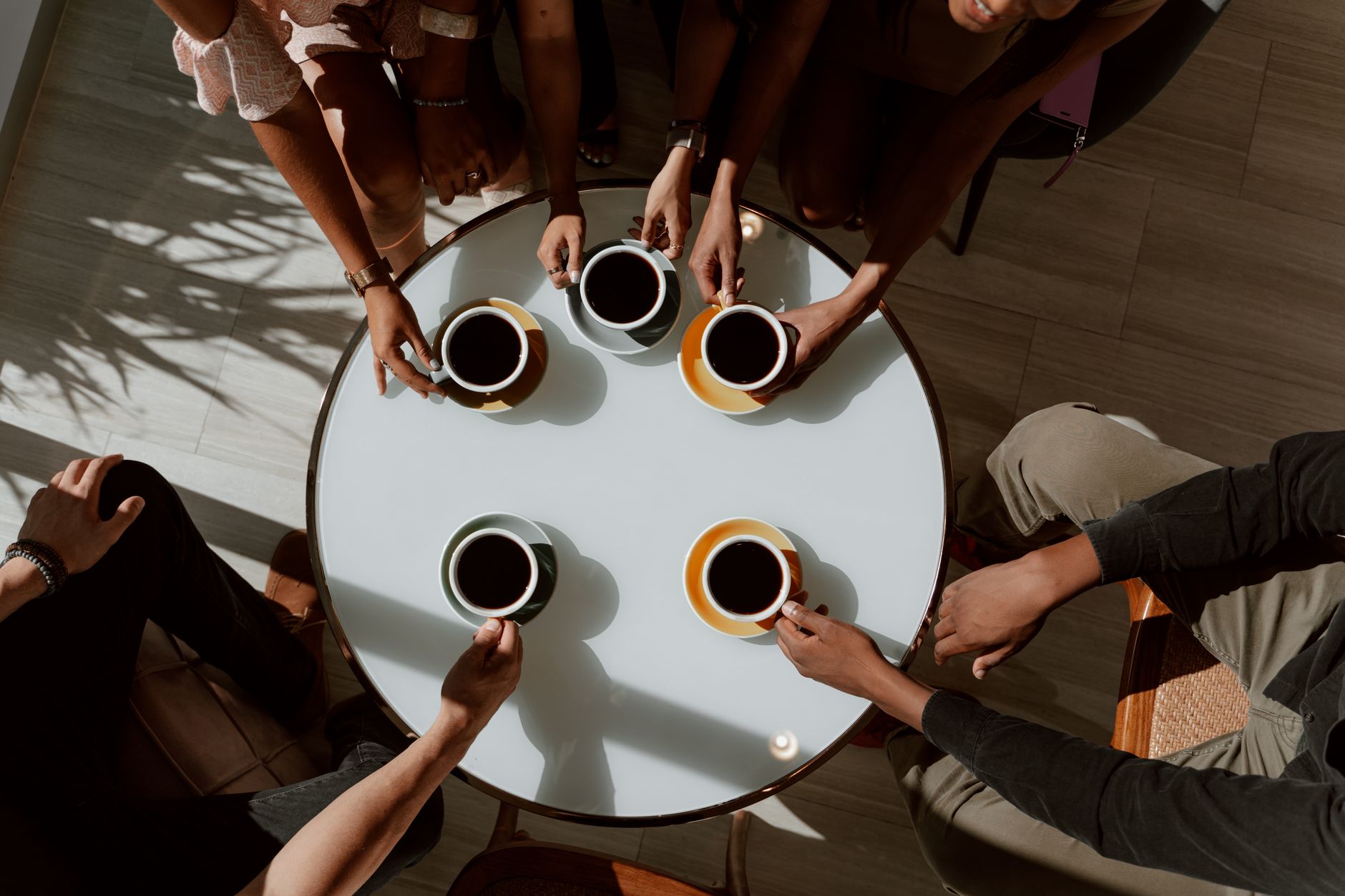 Groupe d’amis prenant un café autour d’une table en café chaleureux.