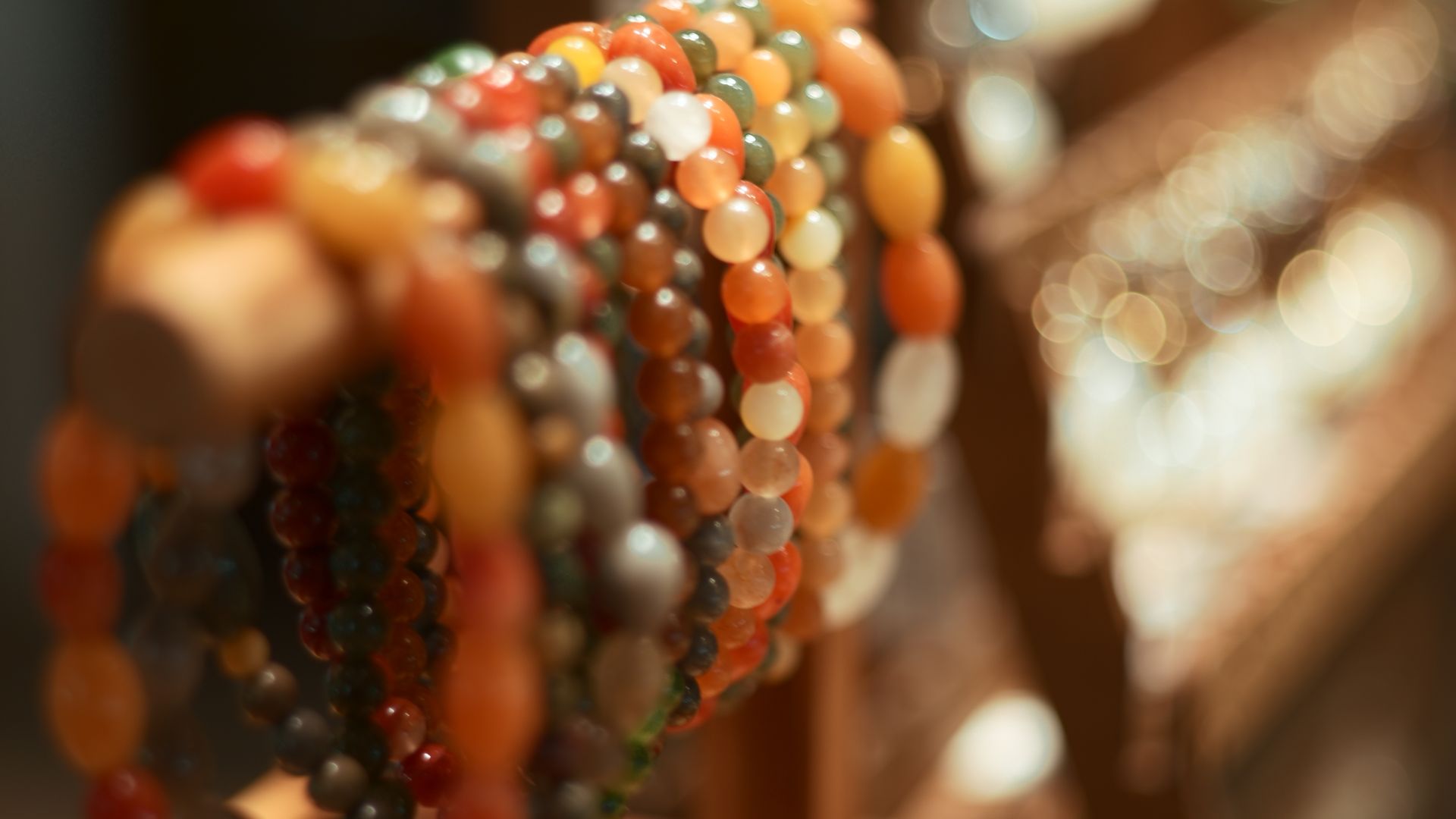 bracelets en pierres naturelles aux teintes variées, empilés sur un présentoir en bois