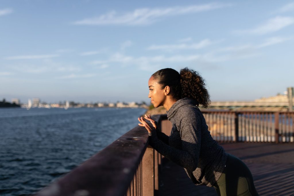 Une personne en tenue de sport marque une pause au bord de l eau au lever du jour