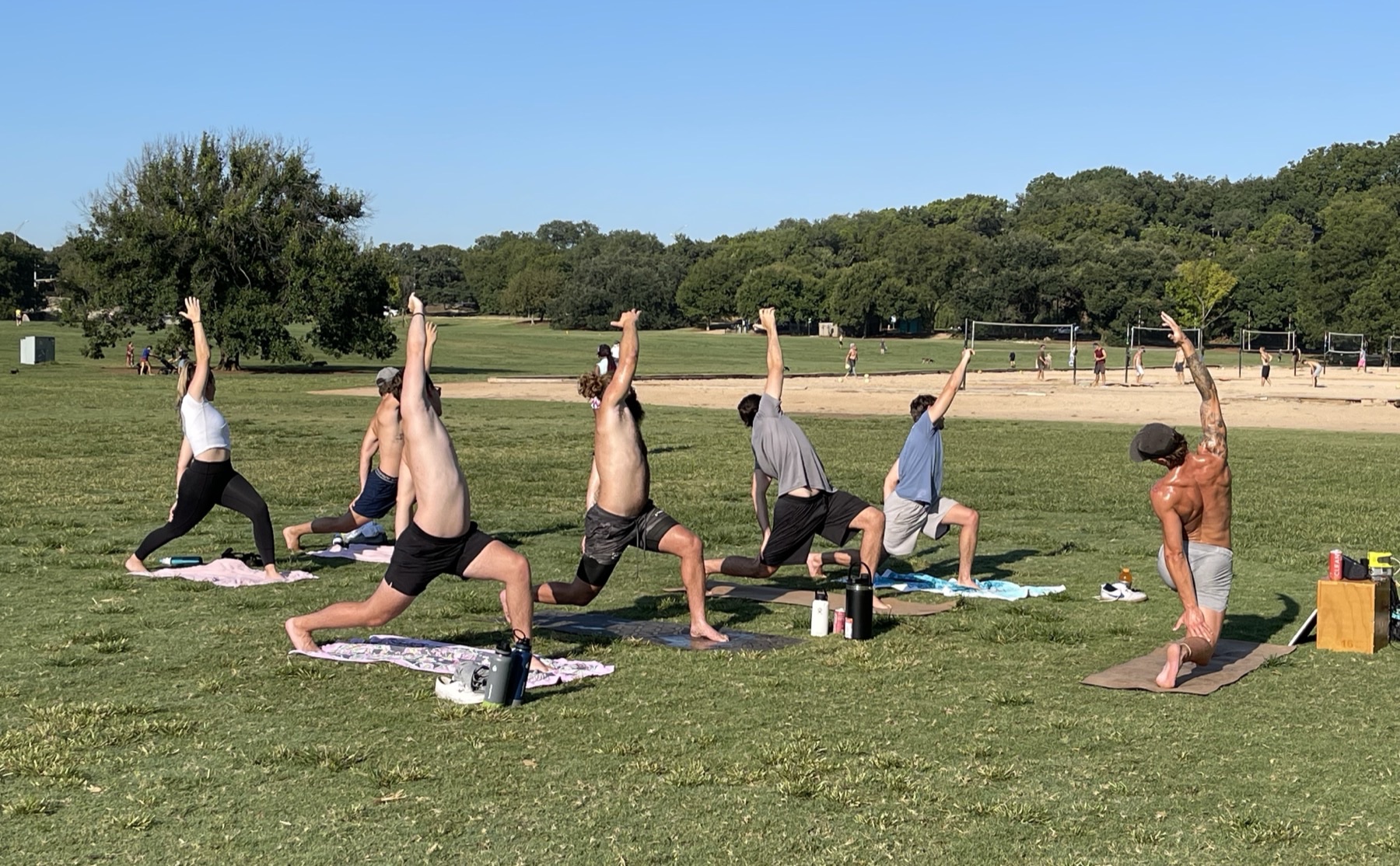 groupe qui suit un cours de yoga en plein air dans un parc, niveaux et âges mélangés
