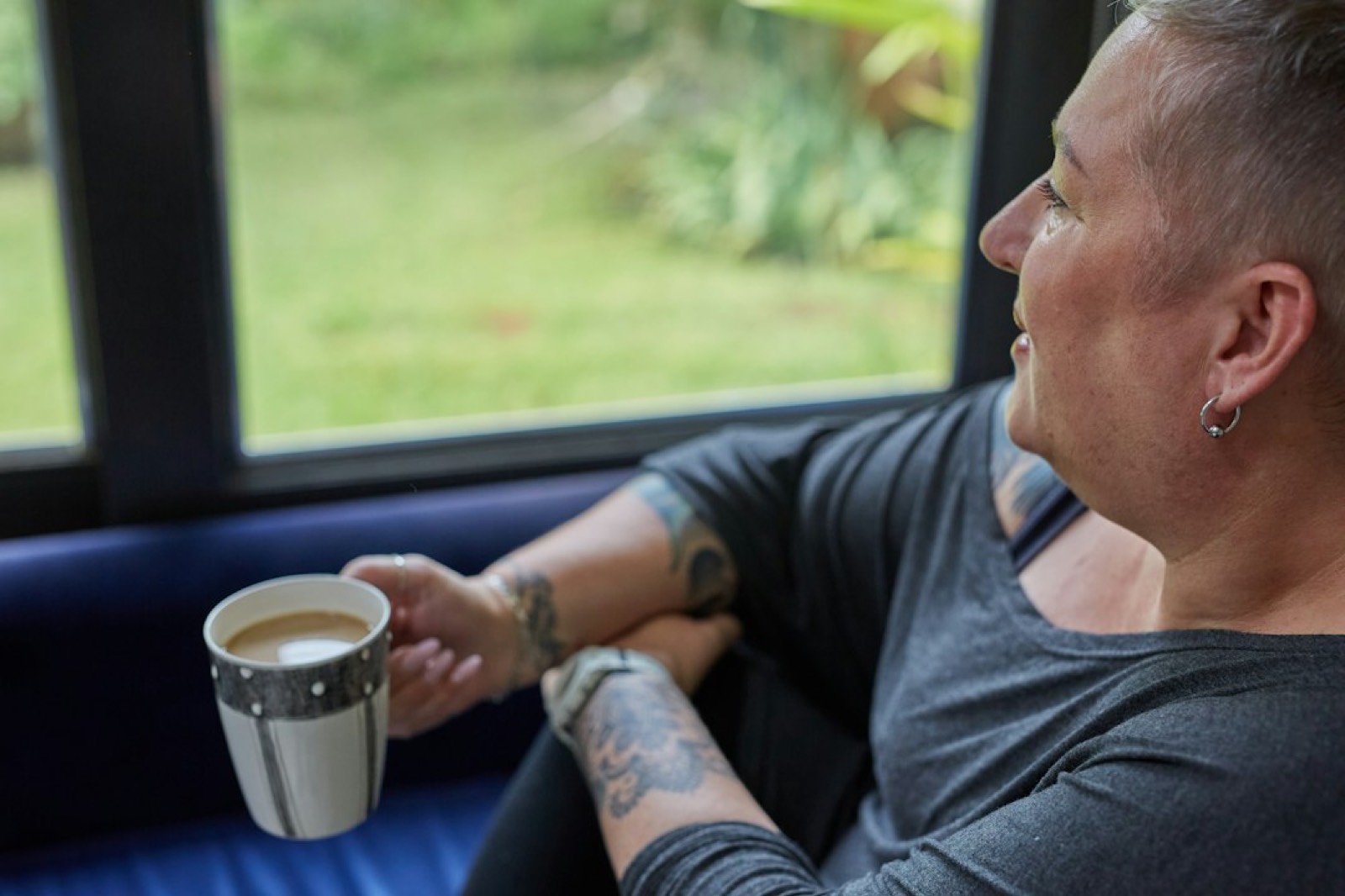 Deux mains tenant une tasse près d'une fenêtre, un moment calme à deux